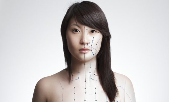Composing of pictures from asian girl and acupuncture model. Concept for acupuncture, alternative medicine, holistic healing. Channels and numbers of acupoints partly visible.